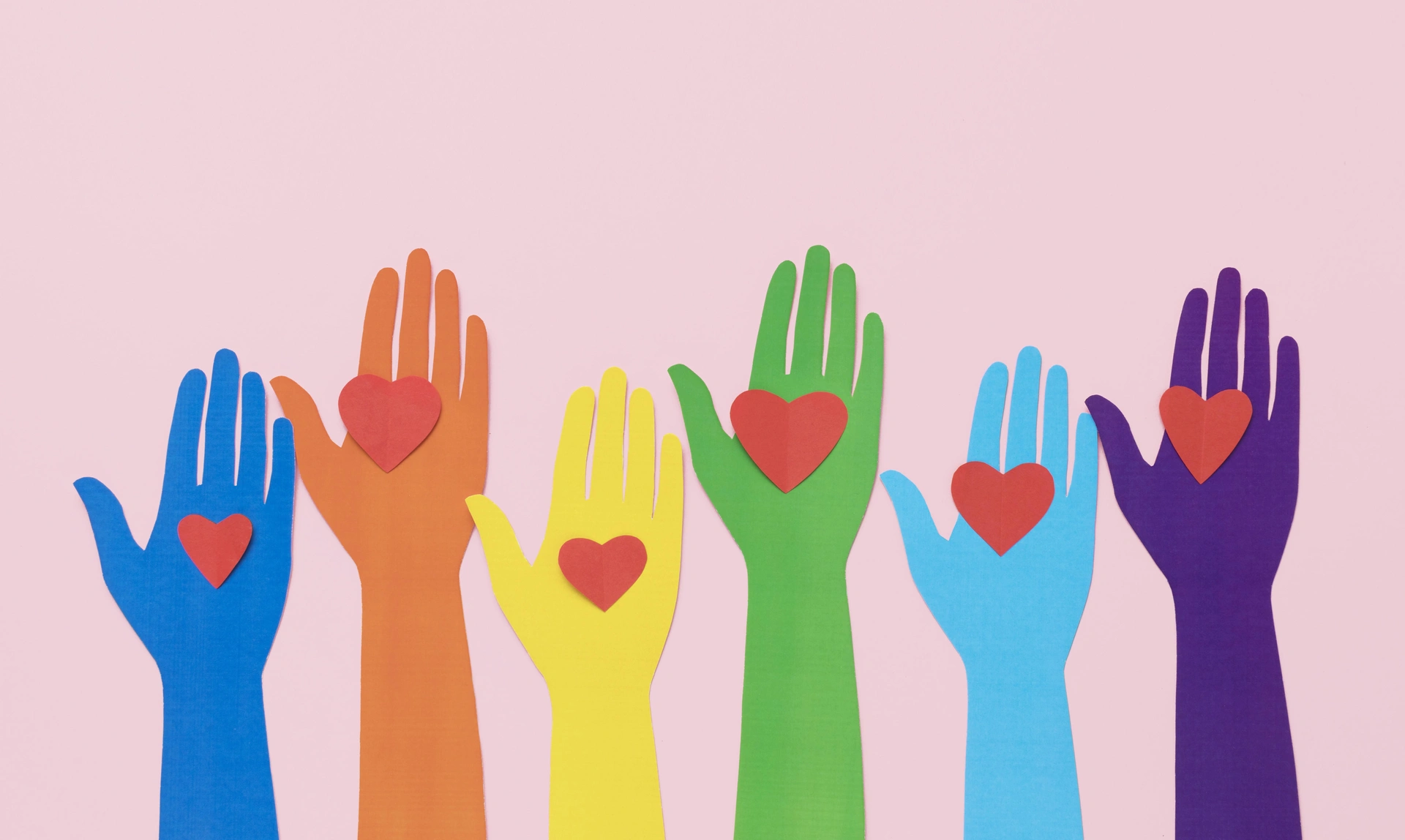 Illustration of lots of hands in different colours raised with hearts on their palms