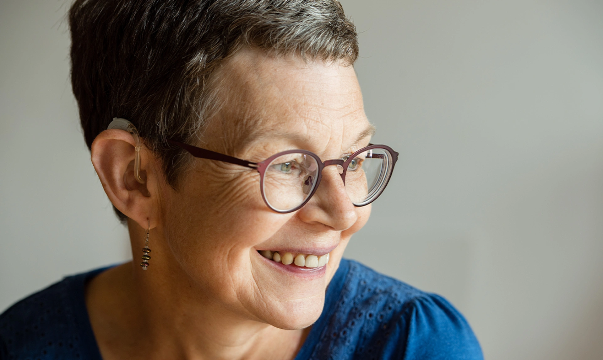 Close up of a woman looking happy wearing a hearing aid