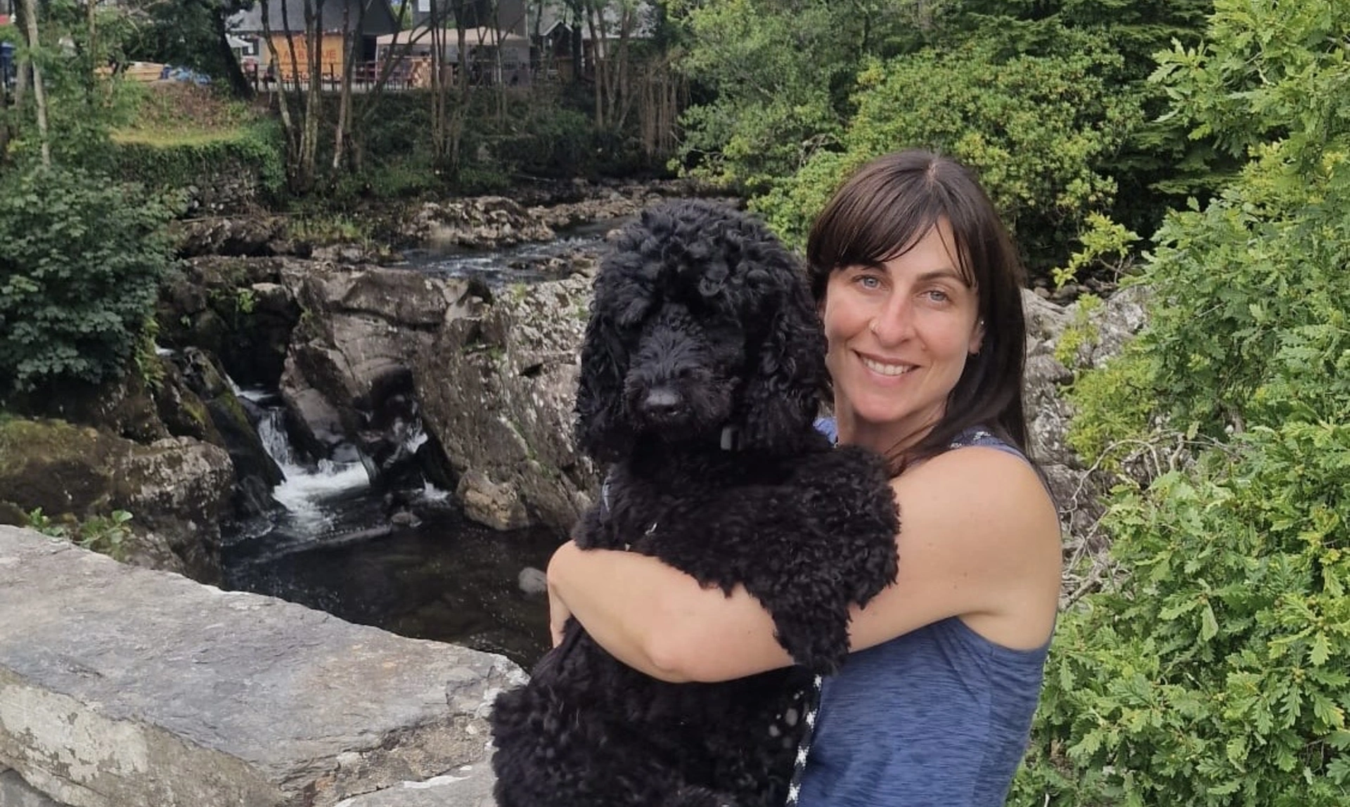 woman cuddling black dog smiling