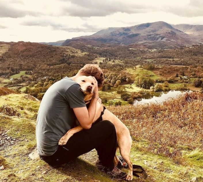 Man hugging golden labrador looking over view