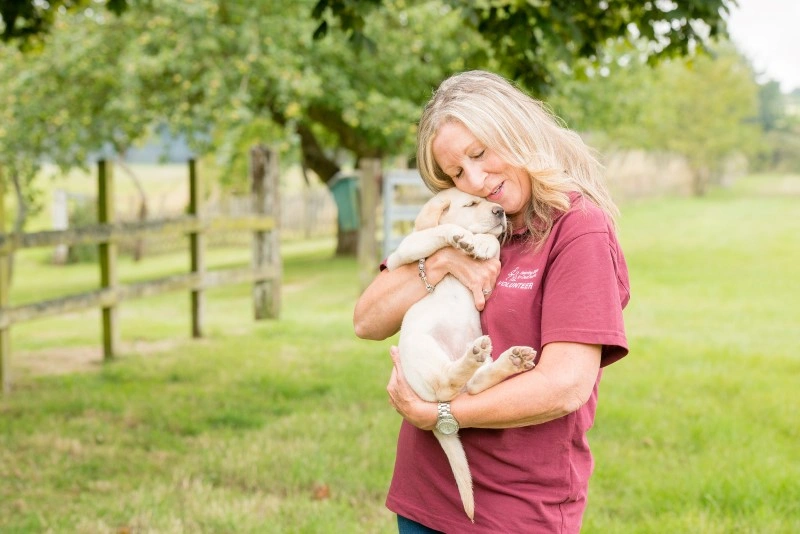 Woman in Hearing Dogs tshirt hugging golden puppy