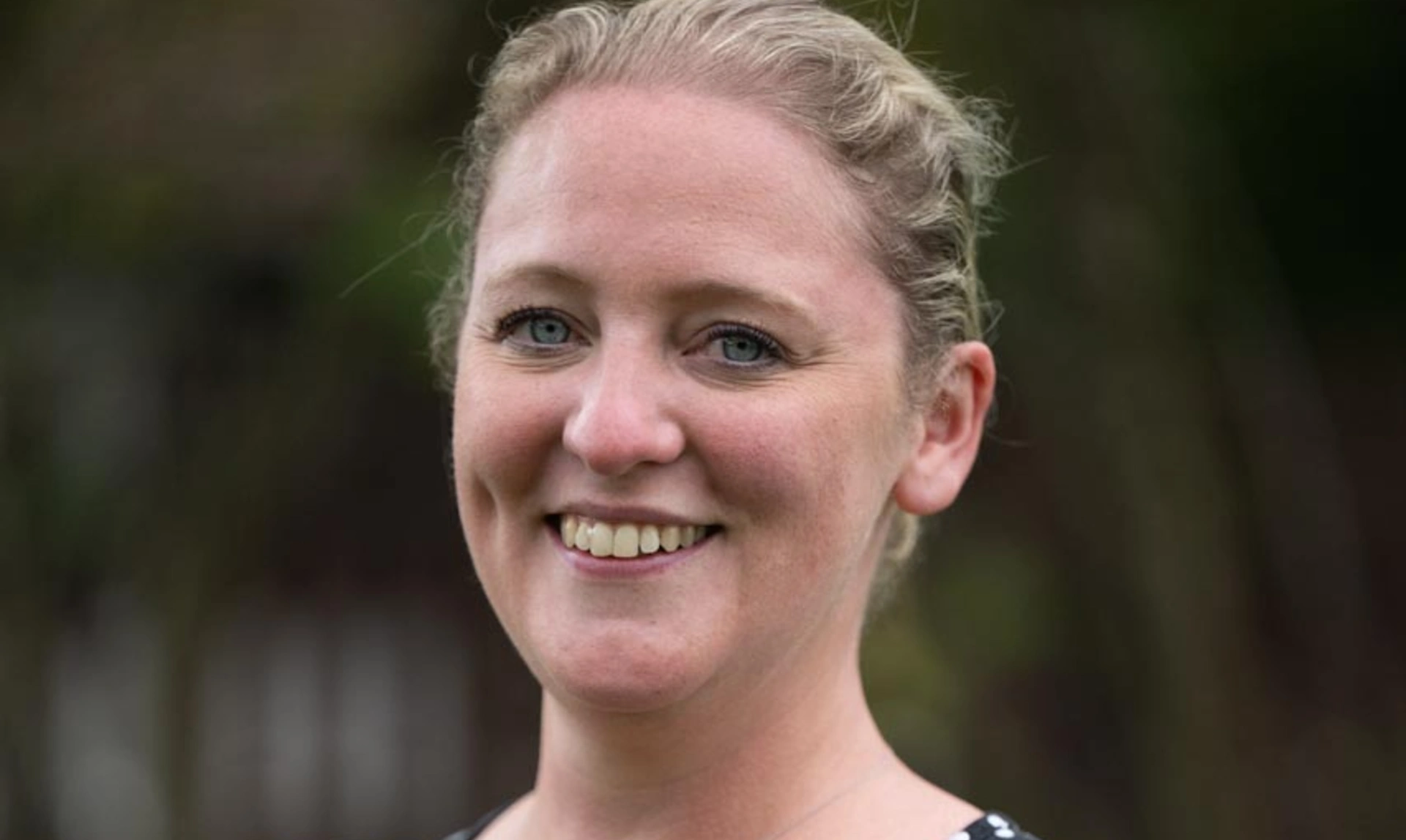 a mid shot of a woman smiling wearing a black with white polka dot dress