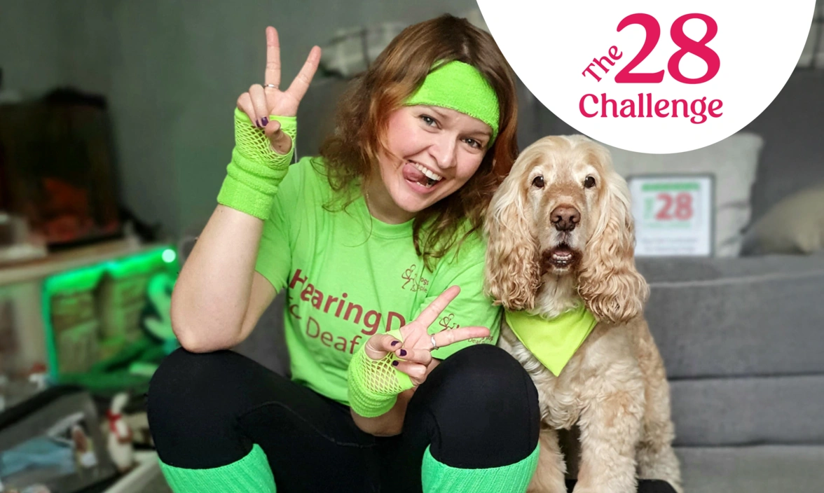 A woman in a sweatband and leg warmers sat next to a dog smiling with the words the 28 challenge in the top right corner