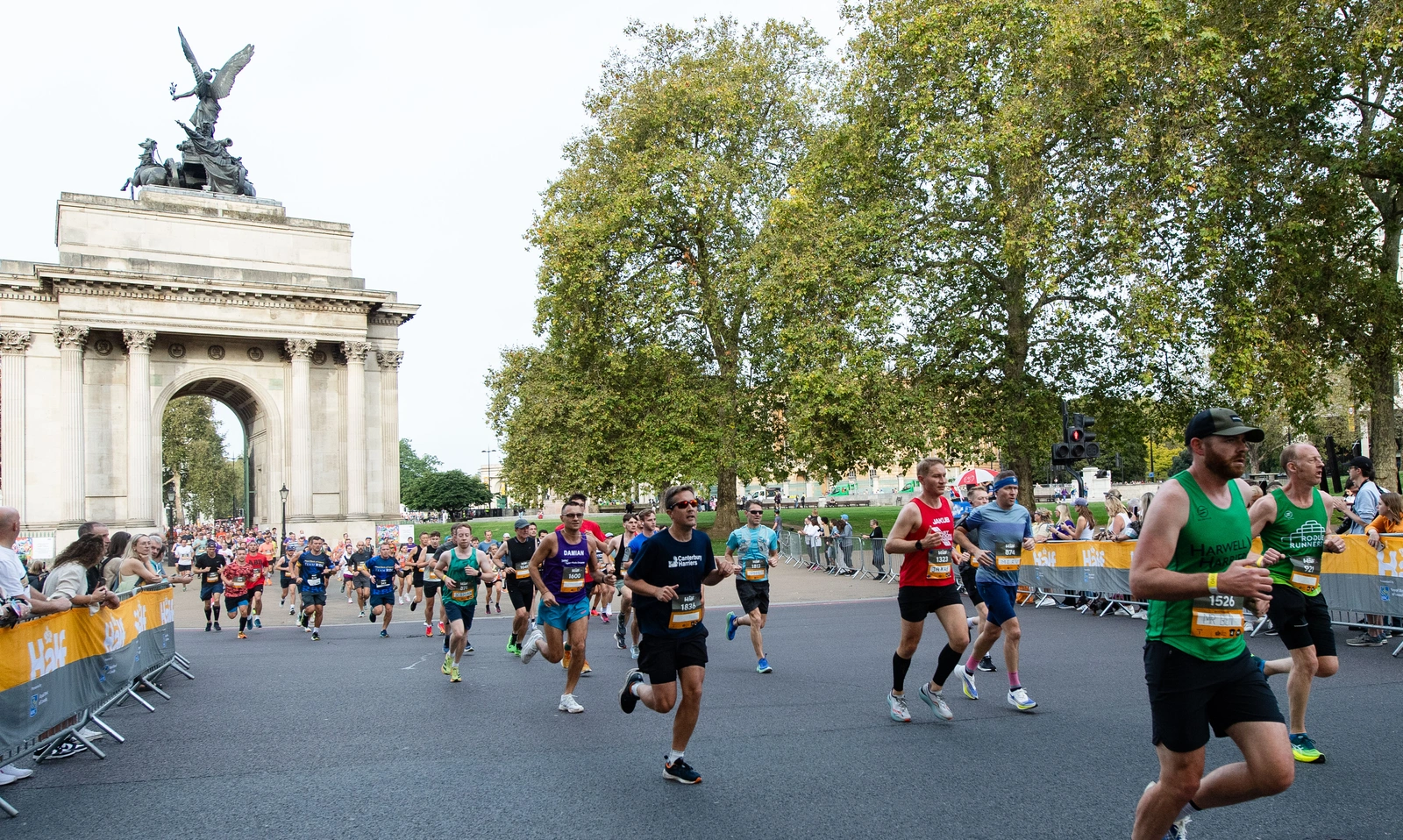 A group of runners are shown passing through the Wellington Arch at Hyde Park
