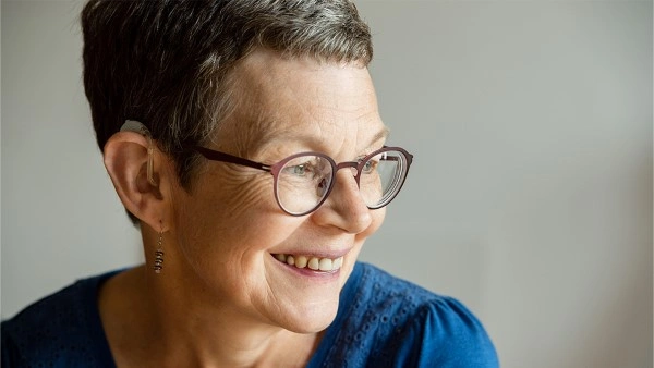 Woman with short dark hair wearing a blue jumper smiling