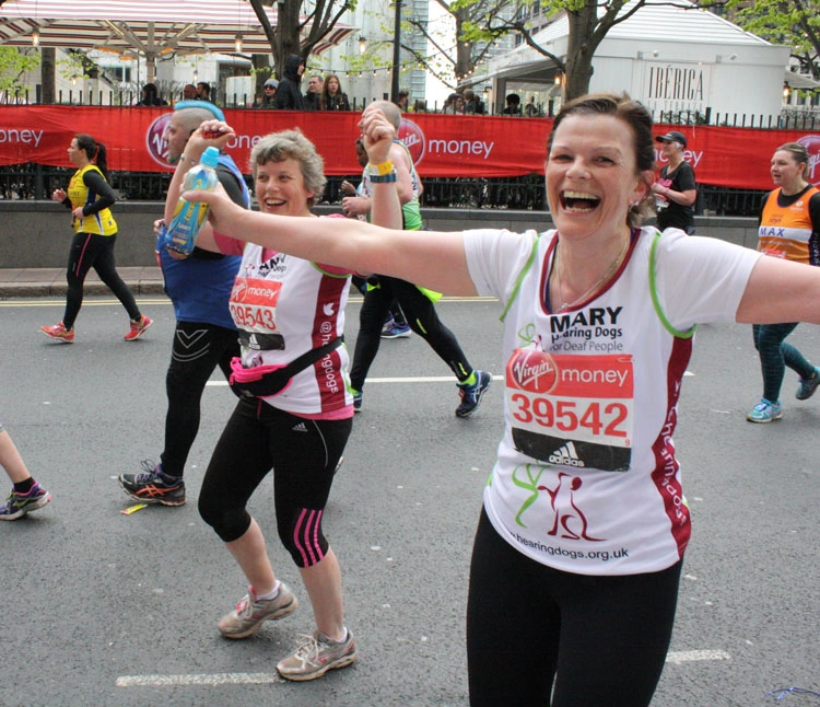 Two smiling Hearing Dogs runners in branded running tops