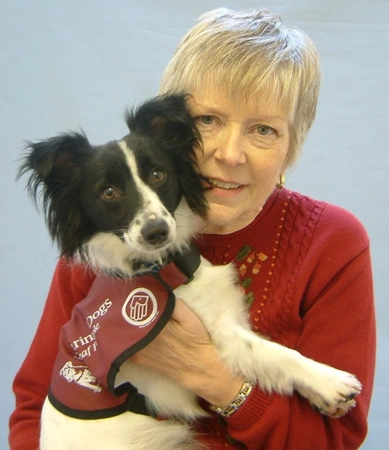Hearing dog Ria being held by woman in red jumper