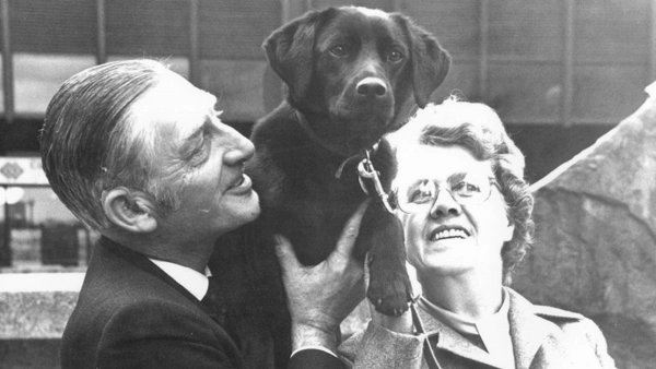 Black and white image of man, woman and black Labrador dog