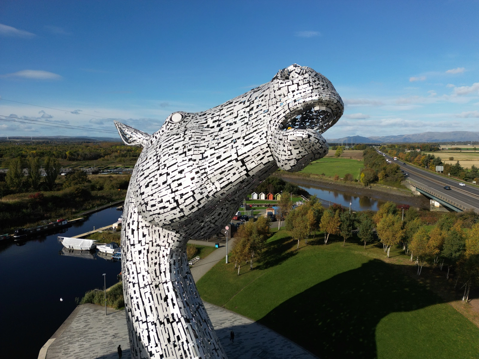An aerial photo of one of the large steel horse head monuments called the Kelpies. It resembles a horse rearing its head.