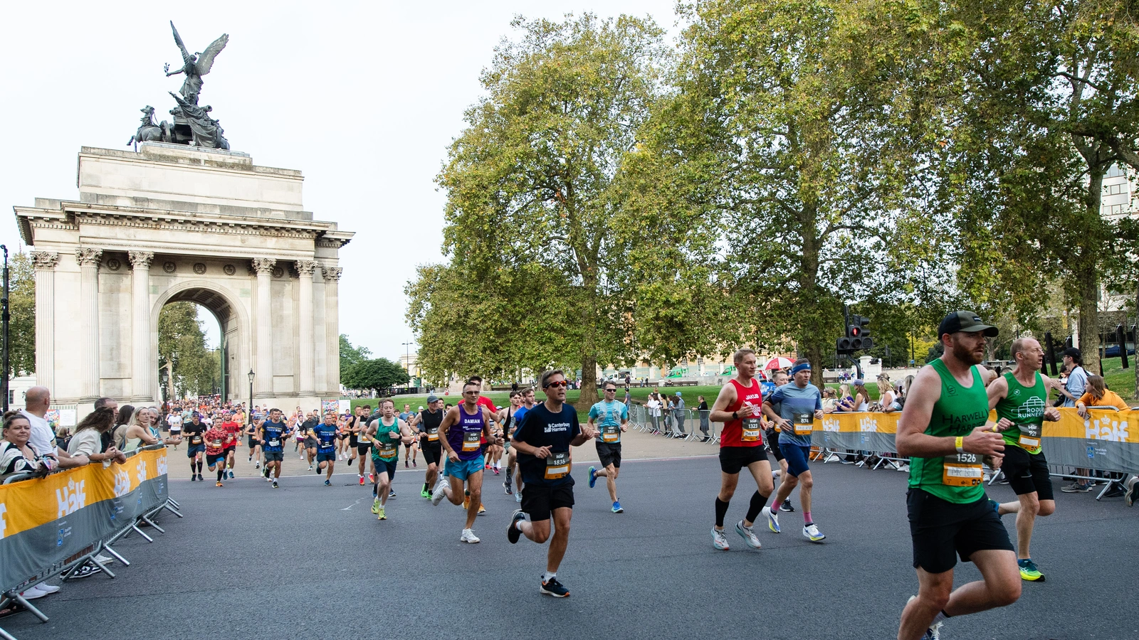 A group of runners are shown passing through the Wellington Arch at Hyde Park